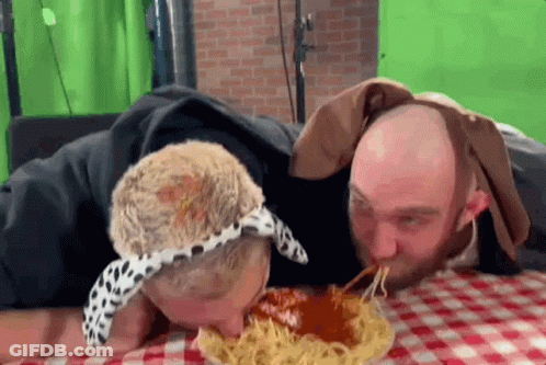Two Men Are Eating Spaghetti Together On A Checkered Table Cloth . GIF