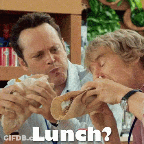 Two Men Are Eating Tacos Together And The Word Lunch Is Above Them . GIF
