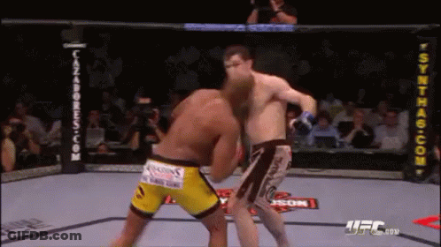 Two Men Are Fighting In A Boxing Ring . One Of The Men Is Wearing Yellow Shorts . GIF