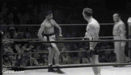 Two Men Are Fighting In A Boxing Ring With A Referee In The Background . GIF