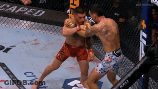 Two Men Are Fighting In A Boxing Ring With The Word Caped On The Wall Behind Them . GIF