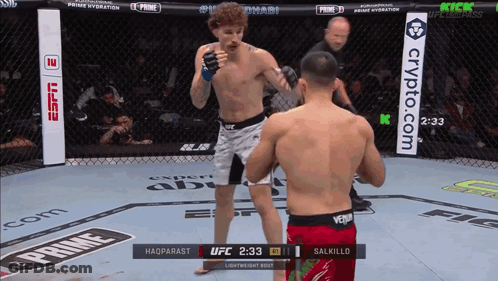 Two Men Are Fighting In A Cage With A Sign That Says Crypto.com In The Background GIF