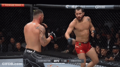 Two Men Are Fighting In A Cage With A Sign That Says Howler Head Above Them GIF