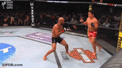 Two Men Are Fighting In A Ring With A Harley Davidson Logo On The Ground GIF
