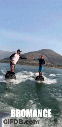 Two Men Are Giving Each Other A High Five While Riding A Wave On A Body Of Water With The Word Bromance Below Them GIF