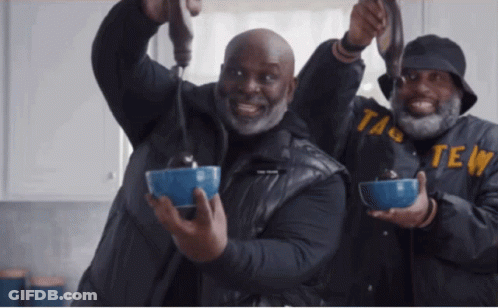 Two Men Are Holding Bowls Of Food And One Of Them Has The Word Taste On His Jacket GIF