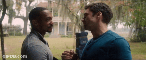 Two Men Are Holding Hands In Front Of A House GIF