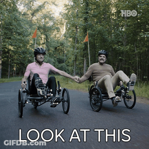 Two Men Are Holding Hands While Riding Three Wheeled Bicycles With The Words Look At This Below Them GIF