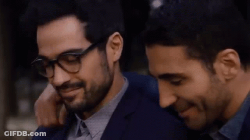 Two Men Are Hugging Each Other And One Of Them Is Wearing Glasses And A Bracelet . GIF
