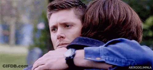 Two Men Are Hugging Each Other In A Park And One Of Them Is Wearing A Watch . GIF