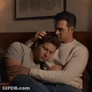 Two Men Are Hugging Each Other On A Couch In A Living Room . GIF