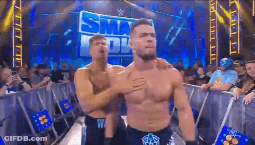 Two Men Are Hugging In Front Of A Sign That Says ' Smackdown ' GIF