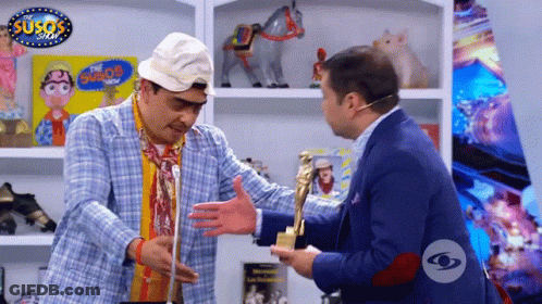 Two Men Are Hugging In Front Of A Sign That Says Susos GIF
