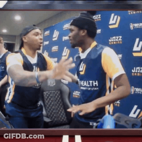 Two Men Are Hugging In Front Of A Wall That Has The Word Jazz On It GIF