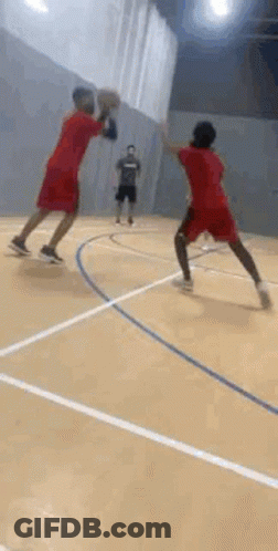 Two Men Are Jumping In The Air On A Basketball Court While Holding Hands . GIF