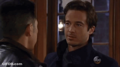 Two Men Are Kissing In Front Of A Window . GIF