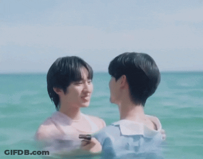 Two Men Are Kissing In The Ocean While One Is Holding A Cell Phone GIF