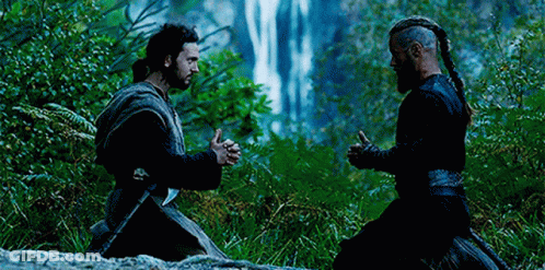 Two Men Are Kneeling In Front Of A Waterfall . GIF