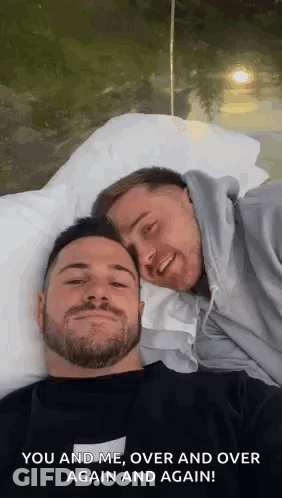 Two Men Are Laying On A Bed With Their Heads Together And Smiling . GIF