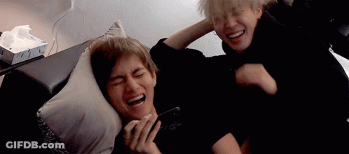 Two Men Are Laying On A Couch And Laughing While One Of Them Is Holding A Cell Phone . GIF
