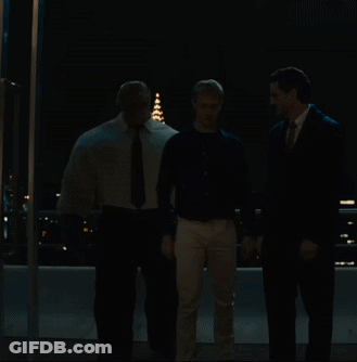 Two Men Are Looking At A Fireworks Display Over A City At Night GIF
