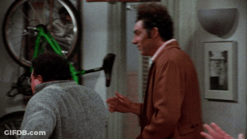 Two Men Are Looking At A Green Bicycle That Is Hanging On A Wall GIF