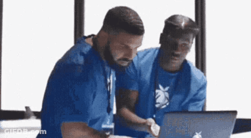 Two Men Are Looking At A Laptop Computer . GIF