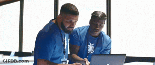 Two Men Are Looking At A Laptop Computer . GIF