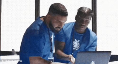 Two Men Are Looking At A Laptop Together . GIF