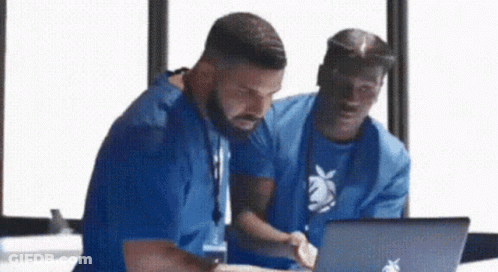 Two Men Are Looking At A Laptop Together . GIF