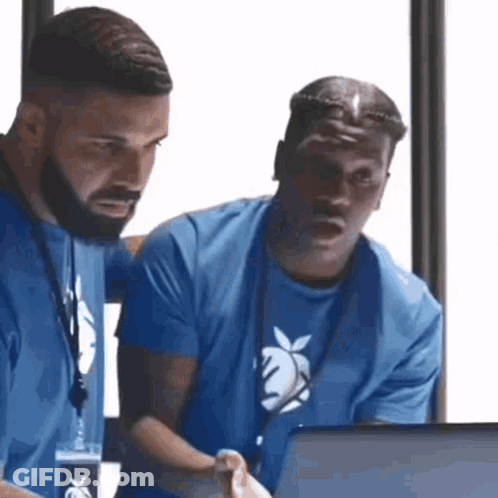 Two Men Are Looking At A Laptop Together . GIF