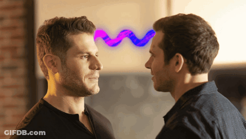 Two Men Are Looking At Each Other With A Purple And Blue Wave Behind Them GIF