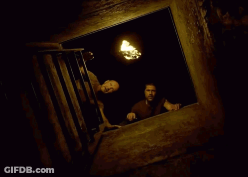 Two Men Are Looking Out A Window At A Torch . GIF