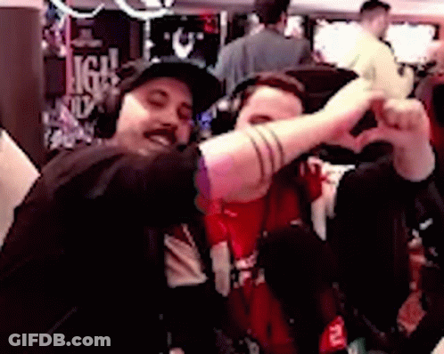 Two Men Are Making A Heart Shape With Their Hands While Sitting Next To Each Other . GIF