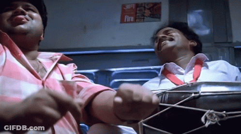 Two Men Are Playing A Drum In Front Of A Fire Sign GIF
