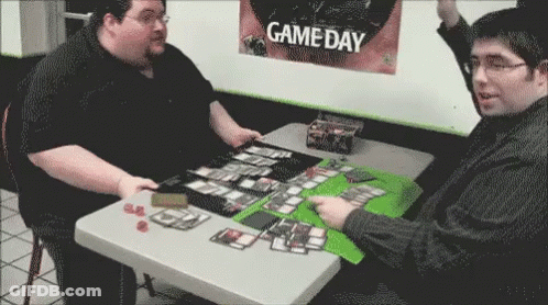Two Men Are Playing A Game At A Table In Front Of A Game Day Poster . GIF