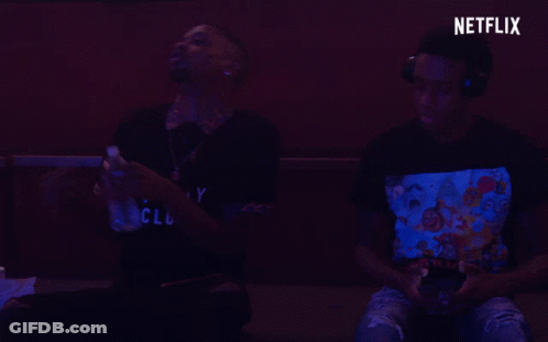 Two Men Are Playing A Video Game With A Netflix Logo Behind Them GIF