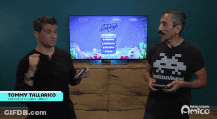 Two Men Are Playing A Video Game With Jimmy Tallarico Standing Behind Them GIF