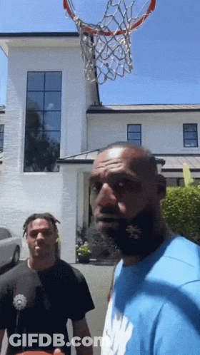 Two Men Are Playing Basketball In Front Of A White Building GIF
