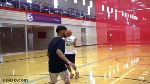 Two Men Are Playing Basketball On A Court In Front Of A Sign That Says ' Champions ' On It GIF