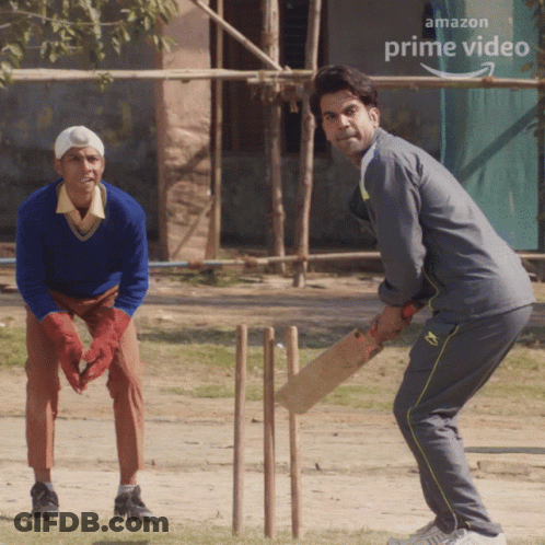 Two Men Are Playing Cricket In Front Of An Amazon Prime Video Banner GIF