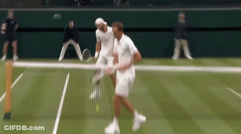 Two Men Are Playing Tennis On A Court And One Of Them Is Holding A Tennis Racquet GIF