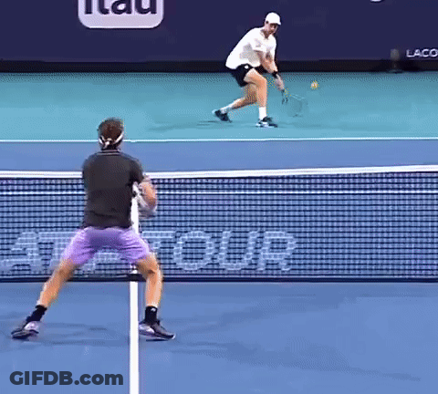 Two Men Are Playing Tennis On A Court With A Sign That Says Tour GIF
