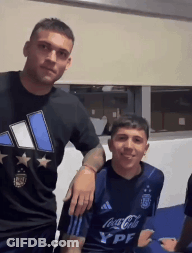 Two Men Are Posing For A Picture And One Has A Coca Cola Shirt On GIF