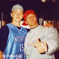Two Men Are Posing For A Picture And One Is Wearing A North Carolina Jersey GIF