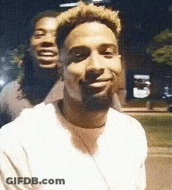 Two Men Are Posing For A Picture Together And One Of Them Is Smiling . GIF