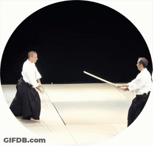 Two Men Are Practicing Martial Arts With Swords In A Circle GIF