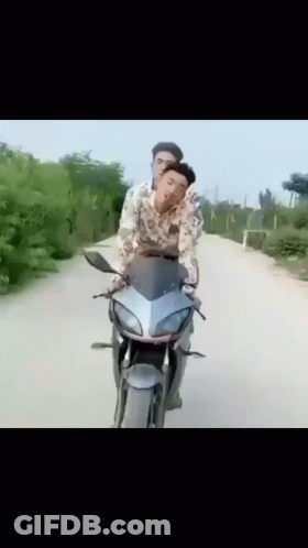 Two Men Are Riding A Motorcycle On A Road GIF