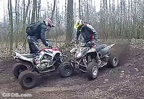 Two Men Riding Four Wheelers On Dirt Road GIF
