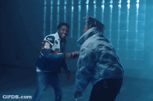 Two Men Are Shaking Hands In A Dark Room And One Has A Jacket That Says ' Audi ' On The Back GIF